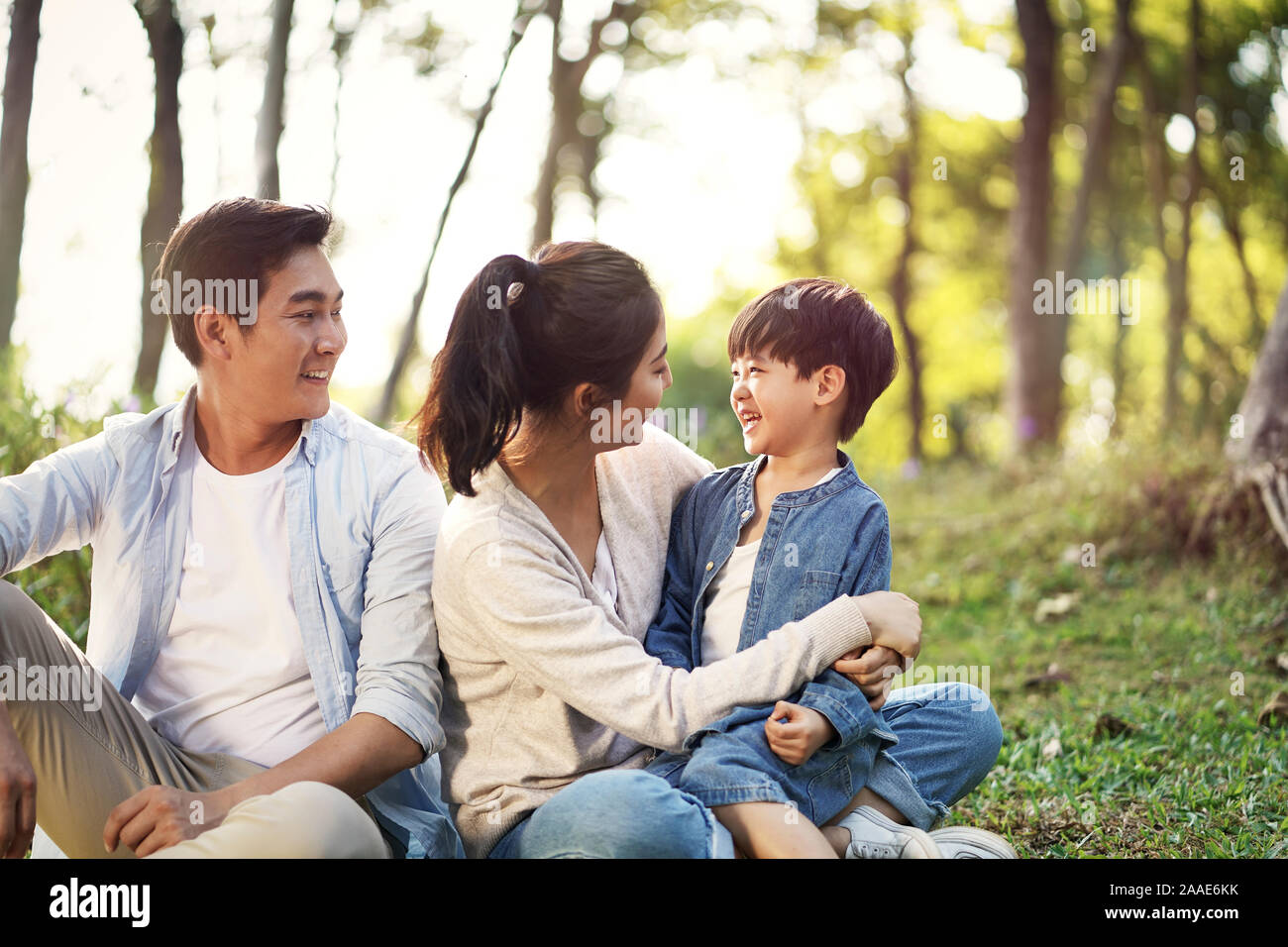Asiatische Familie Mutter Vater und Sohn sitzen auf Gras relaxen Spaß draußen im Park Stockfoto