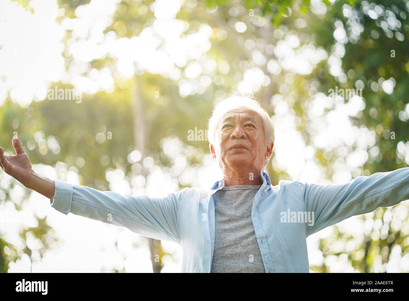 Senior asiatischer Mann genießen die frische Luft gehen mit offenen Armen draußen im Park Stockfoto