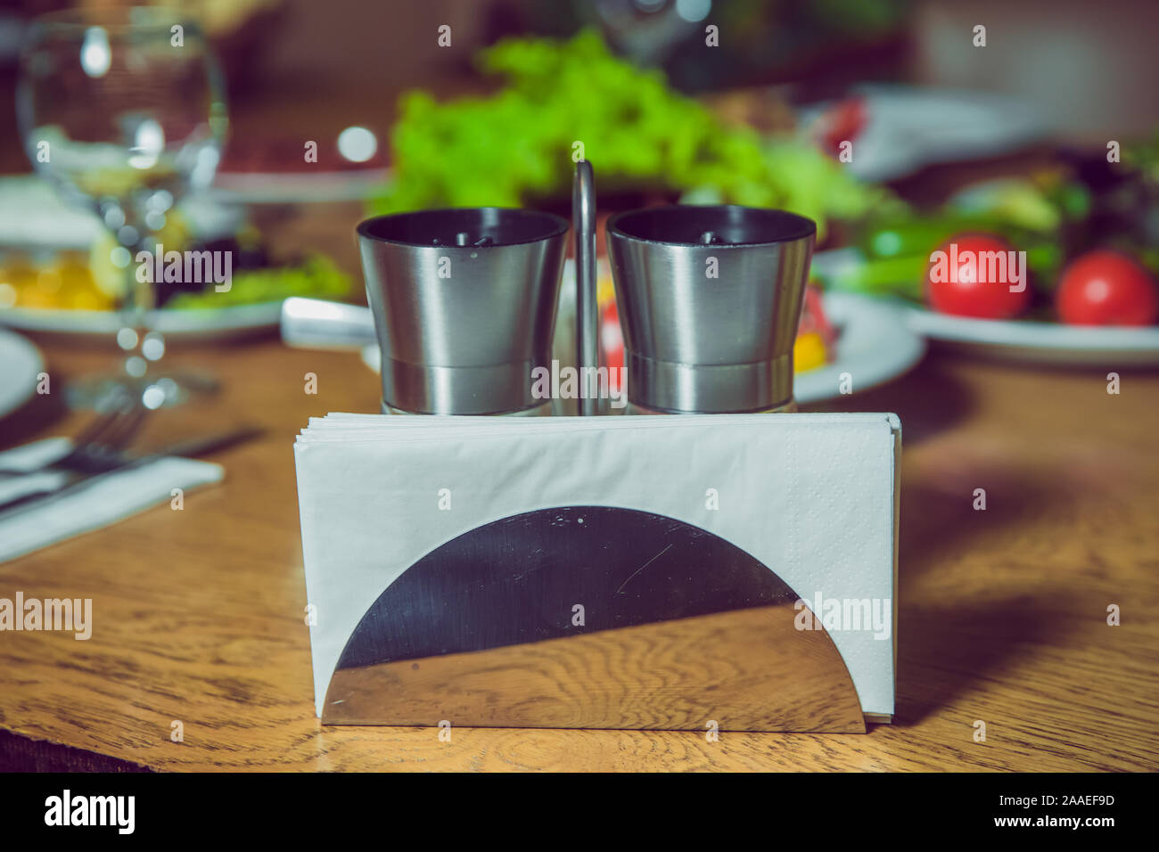 Weiß Servietten in einem Metall Serviettenhalters, Gewürze Salz und Pfeffer auf einem Holztisch, Panoramaaussicht. metall Serviettenhalters auf weißem Hintergrund Stockfoto