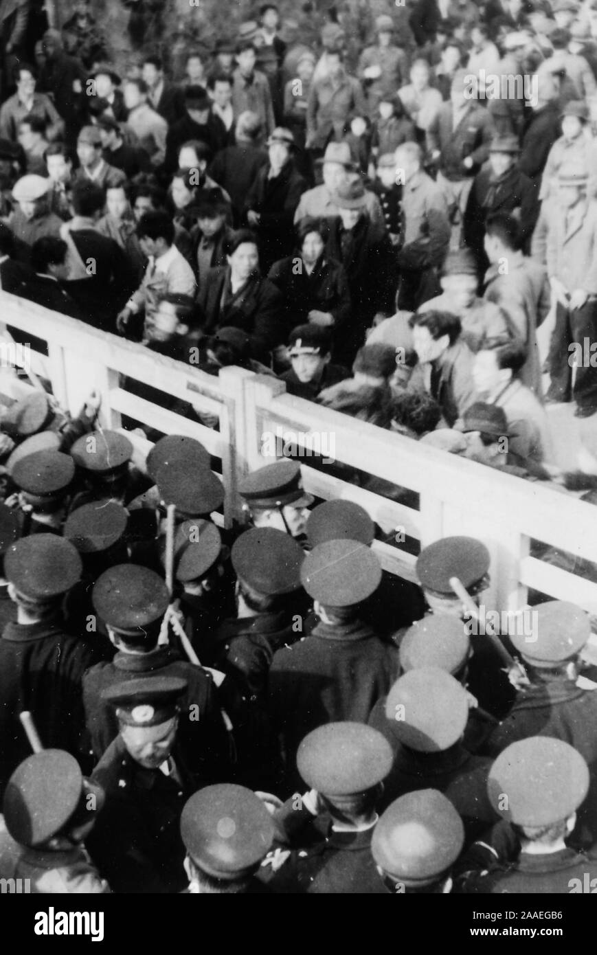 High-Winkel auf ein geschlossenes Tor, mit uniformierten Polizisten auf der einen Seite und einer Menge von zivile Demonstranten auf der anderen Seite wahrscheinlich während einer Arbeit protestieren, die in der Präfektur Fukuoka, Japan, 1950 fotografiert. () Stockfoto