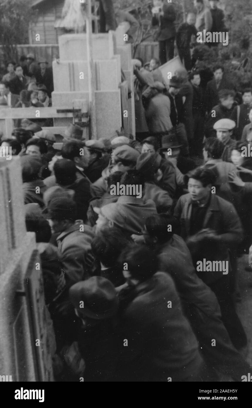Hohe Betrachtungswinkel und einer Menge von Demonstranten, durch ein Gateway (wahrscheinlich, die zu den alten Fukuoka Prefectural Office), während in einer Gewerkschaft demonstration Teilnehmenden an einem bewölkten Tag, in der Präfektur Fukuoka, Japan, 1950. () Stockfoto