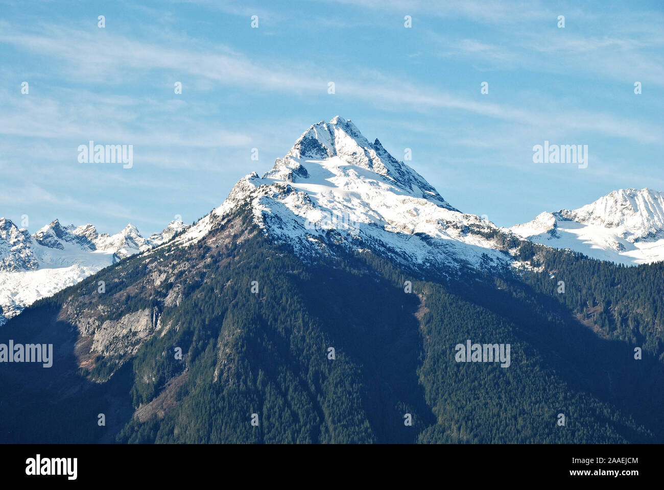 Eine der eindrucksvollen weißen schneebedeckten Gipfeln entlang der Tantalus Bergkette, mit dunkelgrünen Nadelbäumen, und einen klaren, blauen und weißen Himmel Stockfoto