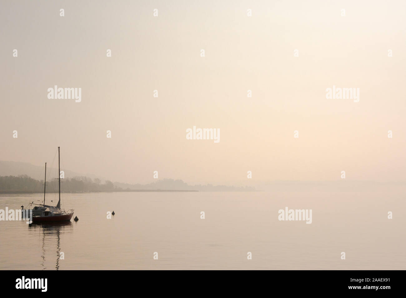 Zwei kleine Segelboote zusammen günstig auf noch Wasser in den frühen Morgenstunden, blasse unruffled Himmel und Wasser mit Platz kopieren Stockfoto