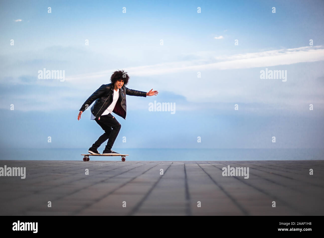 Hübscher junger afro-amerikanische Kerl mit Skateboard mit blauer Himmel, kopieren Raum Stockfoto