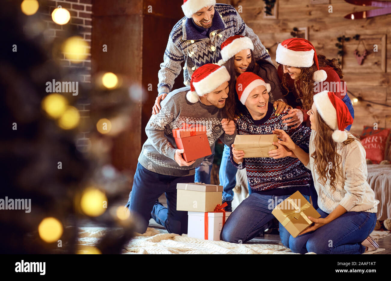 Freunde in Santa's Hüte ändern Geschenke auf der Weihnachtsfeier Stockfoto
