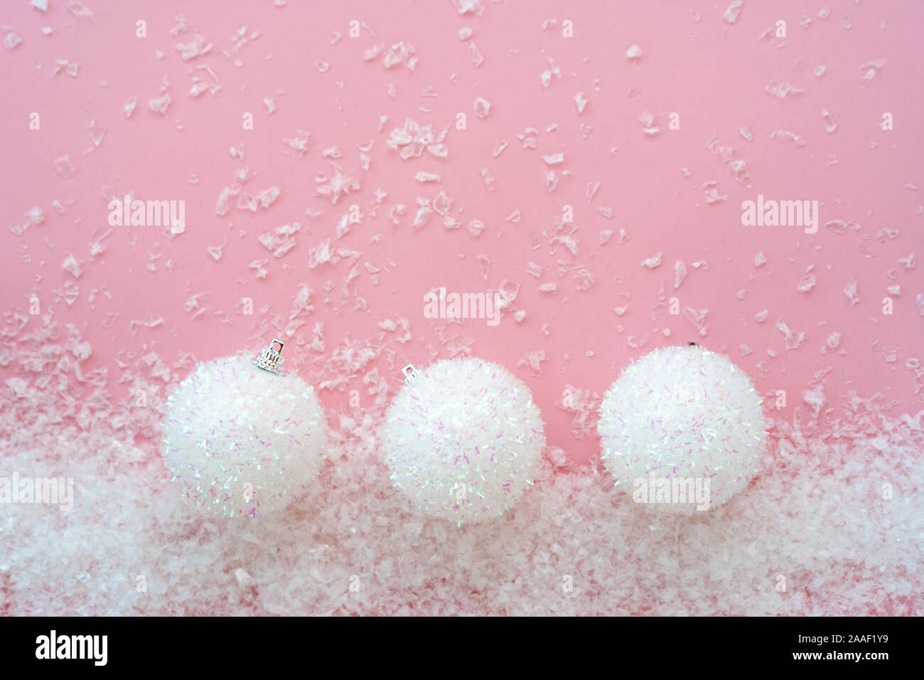 Drei Kreis Weihnachten Kugeln auf dem rosafarbenen künstlichen Schnee Hintergrund Stockfoto