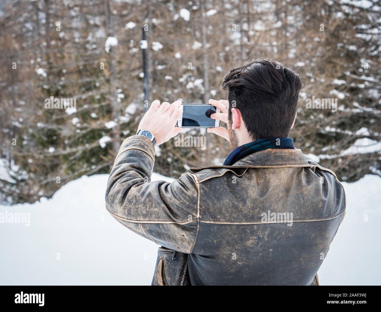 Junger Mann mit Smartphone im Schnee Stockfoto