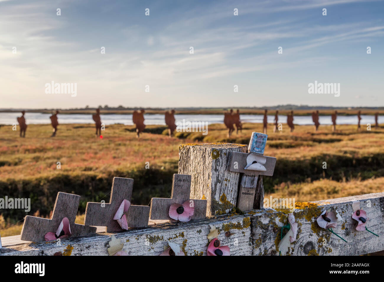 Verdorrte Mohnblumen auf einem Zaun, hinter dem die Silhouetten von Metall WW1 Soldaten März über der Landschaft. Hommage an diejenigen, die ihr Leben im 1.Weltkrieg verloren. Stockfoto