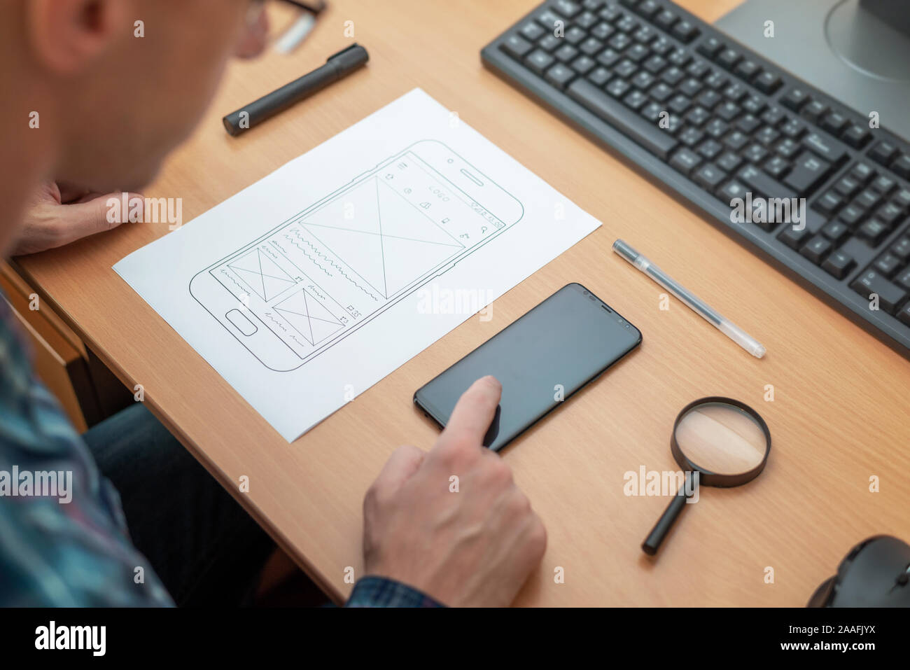 Designer touch Mobiltelefon anzeigen lassen. Konzept der Prüfung Web App. Witeframe mit app Skizze neben. Close Up. Stockfoto