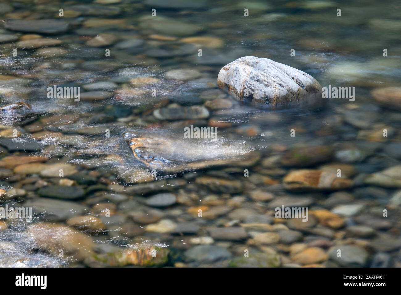 Sonnenlicht glitzernden in unregelmäßig, zufällige Muster auf fließendes Wasser über die Felsen in einem Bergbach Stockfoto