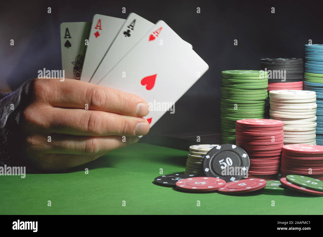 Männliche Hand mit vier Assen Karten und Poker Chips auf dem grünen Tisch Hintergrund. Stockfoto