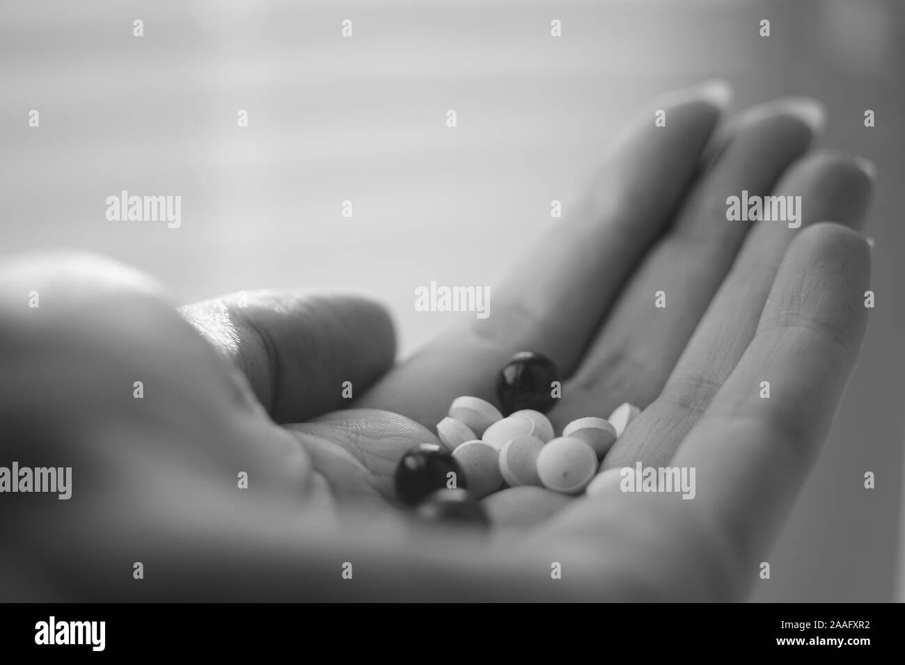 Medizinische Pillen in junge weibliche Hand. Vitamine in der Handfläche. Schwarze und weiße Poto Stockfoto
