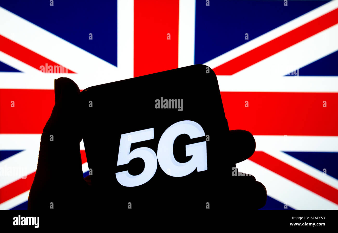 5 G Buchstaben auf einem schwarzen Bildschirm an die Silhouette eines Smartphone in die Hand mit der unscharfen Großbritannien Flagge im Hintergrund. Stockfoto