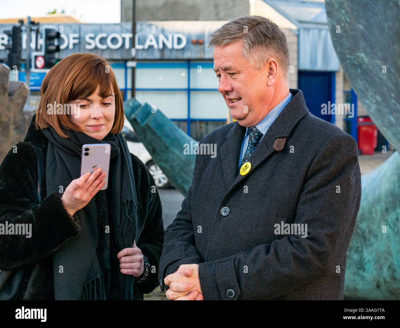 Loanhead, Midlothian, Schottland, Vereinigtes Königreich: 2019 Bundestagswahlkampf. SNP Stellvertretende Vorsitzende Keith Brown MSP mit partei Mitglied am Telefon Stockfoto