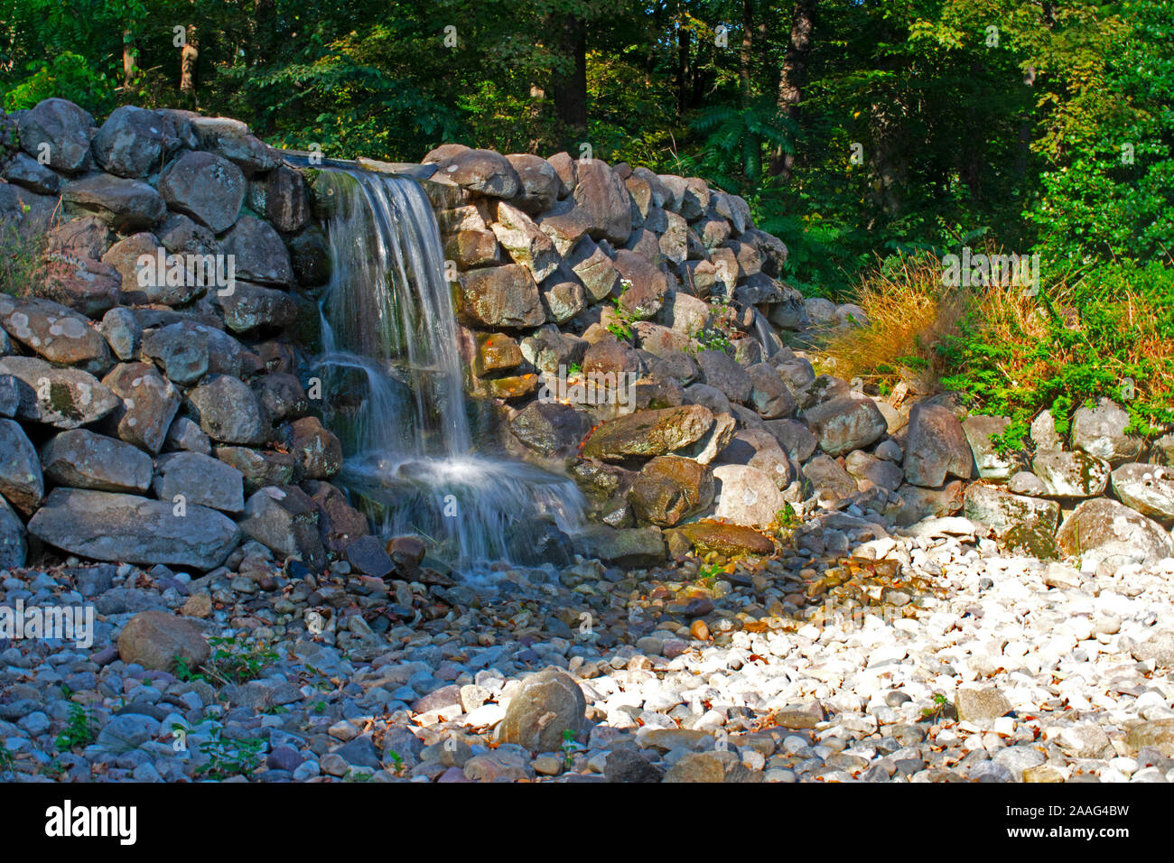 Lange Belichtung Bild eines kleinen, künstlichen Wasserfall cascading auf großen Steinen am Herzog Farmen, Hillsborough County, New Jersey Stockfoto