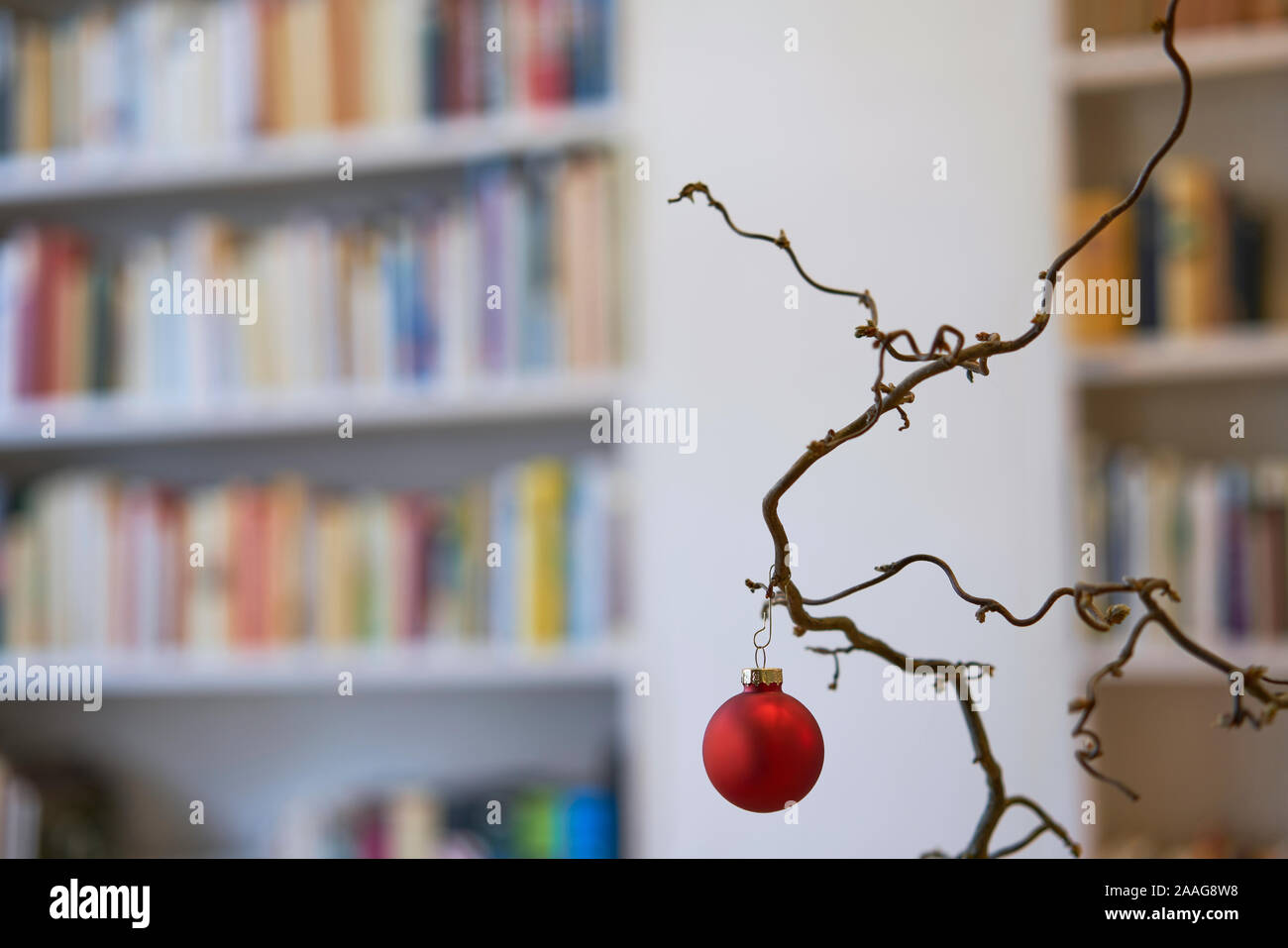 Nahaufnahme eines Red christmas Ball in einer Filiale vor einem unscharfen Hintergrund der Bücherregale Stockfoto