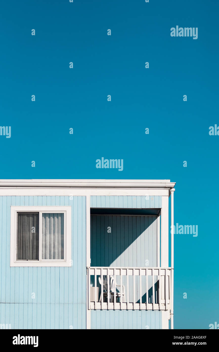 Artsy Blick auf einsame Basic blau Ferienwohnung/hotel Deck und Stuhl aus Kunststoff gegen den blauen Himmel Stockfoto