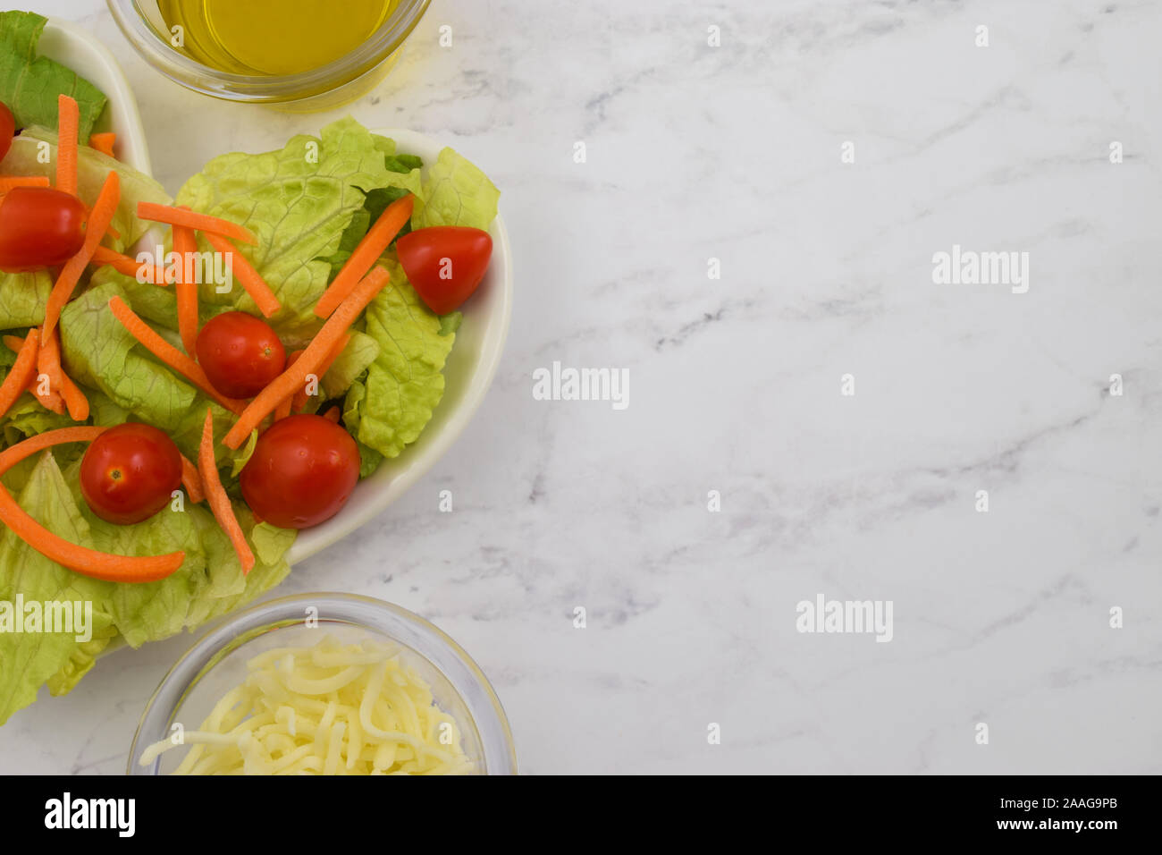 Das gesunde Herz Salat. Römersalat, geschreddert Karotten und Trauben Tomaten bilden eine herzförmige Salat, ist Gnade von seiten von Olivenöl ein Stockfoto