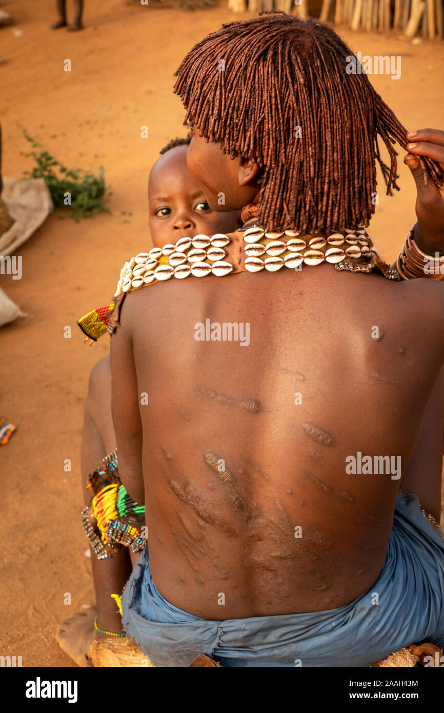 Äthiopien, South Omo, Turmi, Hamar Tribal Dorf, Frau mit Kind Übersicht rituell zurück von Schlagsahne geschrammt Stockfoto
