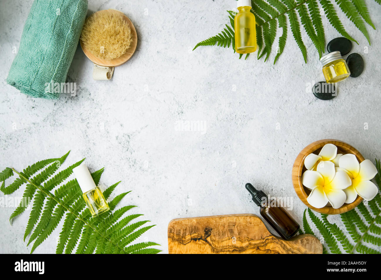 Spa Noch leben flatlay Einstellung mit Frangipani Blüten, Öl Flaschen, Handtuch und Bürste, Massage Steine und grüne Blätter, Wellness und Spa mit c Stockfoto