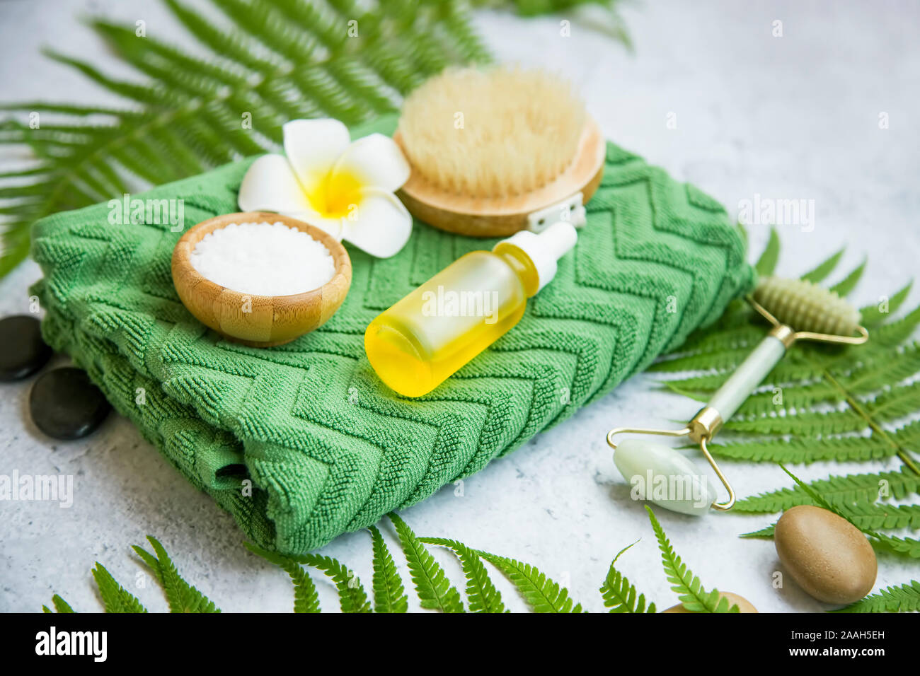 Spa Noch leben Einstellung mit Öl Flasche, Badesalz, Blume, Massage Steine, Handtuch und grüne Blätter, Wellness und Spa Einstellung Stockfoto