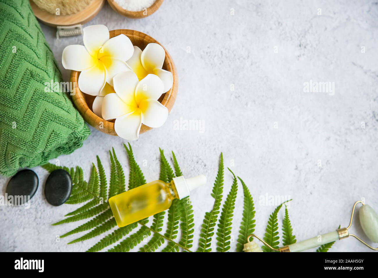 Spa Noch leben Einstellung mit Frangipani Blüten, Öl Flasche, Badesalz, Massage Steine, Handtuch und grüne Blätter, Wellness und Spa Einstellung Stockfoto