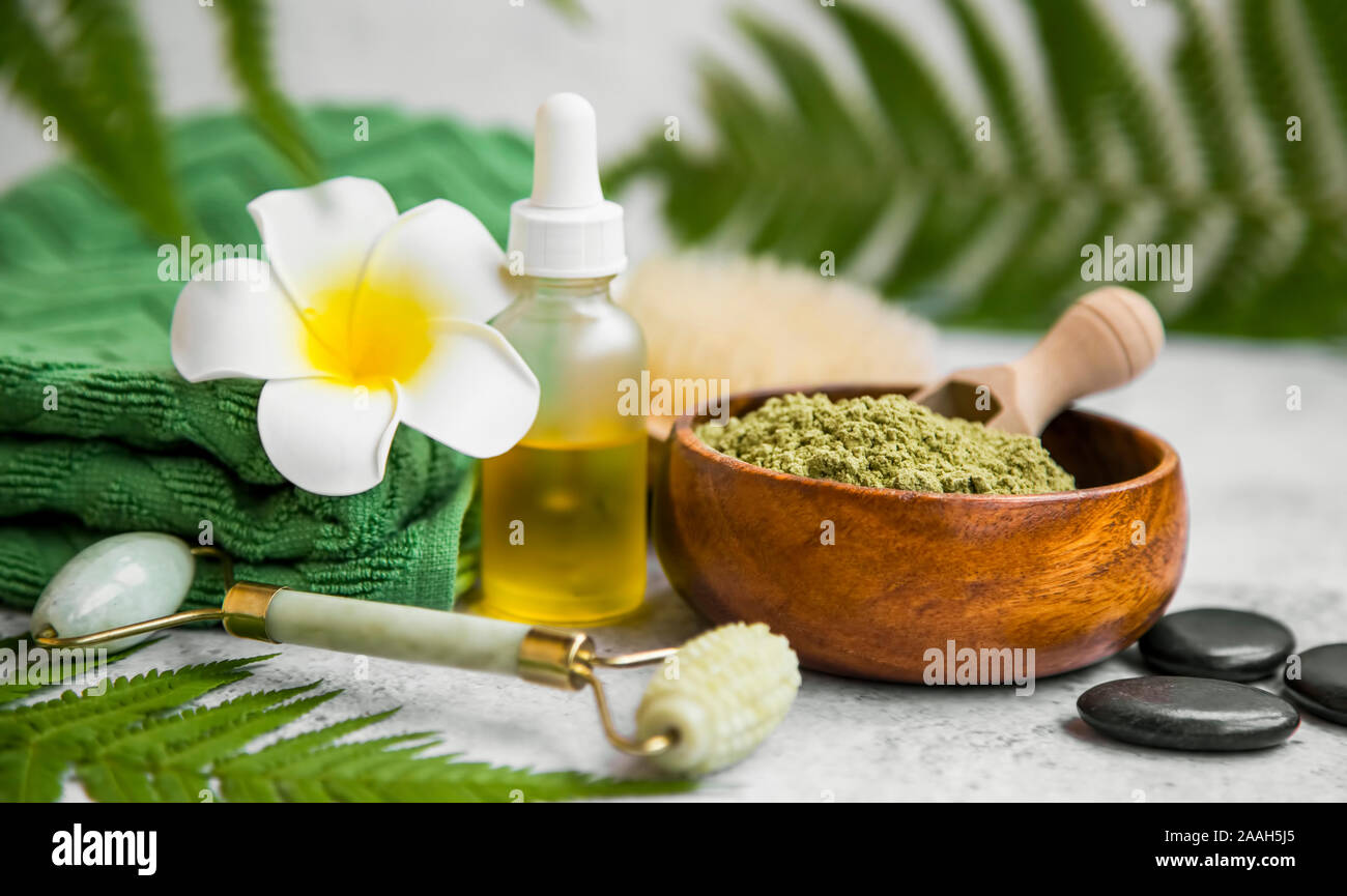 Spa noch Leben mit grünen Blättern, Grüner lehm Pulver zur Herstellung einer Gesichtsmaske, Handtuch, Massage Steine, frangipani Blume und Ölflasche Stockfoto