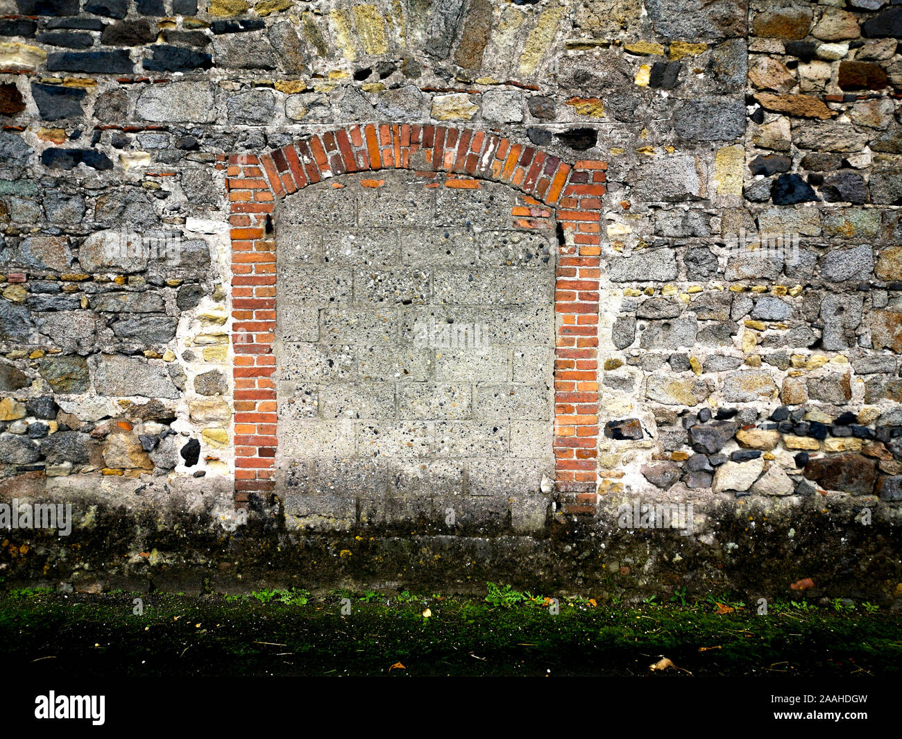 CNahaufnahme einer Mauer aus Stein und Stein mit Gras im Vordergrund Stockfoto