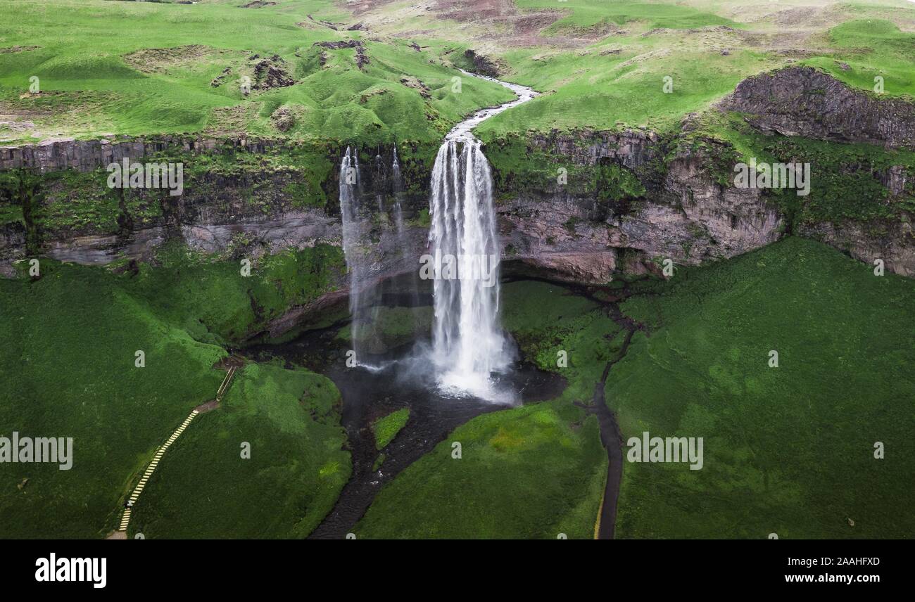 Luftaufnahme, Wasserfall Seljalandsfoss fällt von hohen Felsen, grünes gras landschaft, South Island, Island Stockfoto