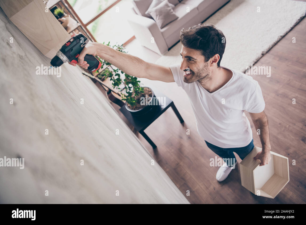 Hohe Betrachtungswinkel Foto von gemischten Rennen 1001 Guy Installation neuer Wandregal mit der Bohrmaschine manuelle Reparatur der neuen Wohnung gerne Handwerker arbeiten mit Freude Stockfoto