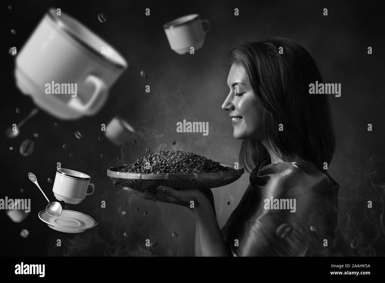 Junge schöne Frau mit gerösteten Kaffeebohnen. Fliegende Kaffeetassen, Untertassen und Löffeln. Konzeptionelle Bild zum Thema Kaffee. Schwarz und Weiß. Stockfoto