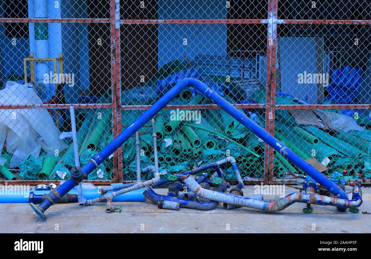 Closeup verworfen Blau gebogen Wasserleitung lehnte sich gegen den Zaun des Lagers, Warten auf Recycling Stockfoto
