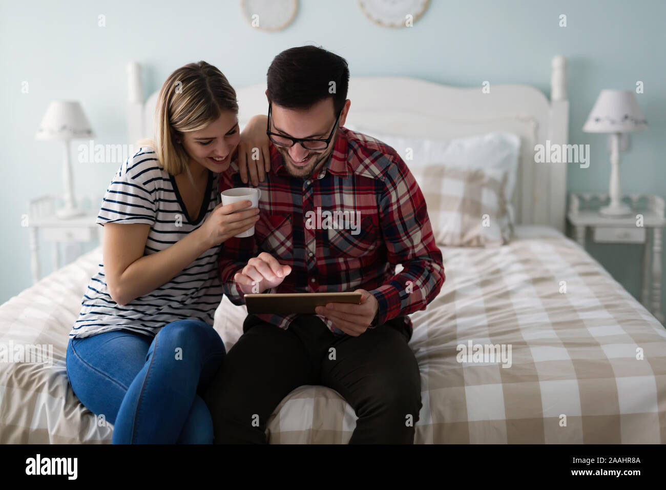Junges attraktives Paar mit Tablet-PC im Schlafzimmer Stockfoto