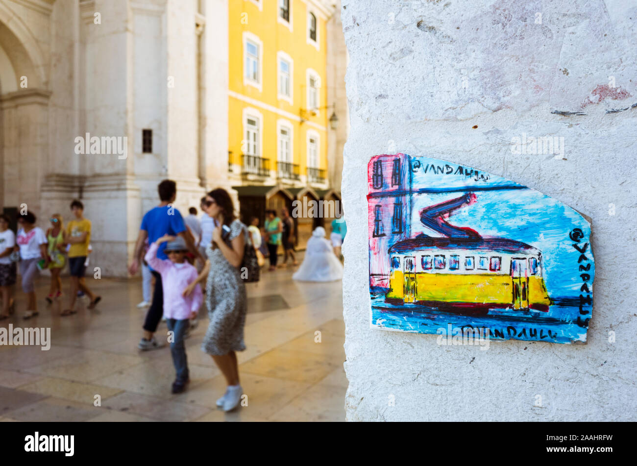 Lissabon, Portugal: Porzellan Plakette entspricht einer alten gelben Straßenbahn an der Rua Augusta Arch. Zufällige Personen im Hintergrund. Stockfoto