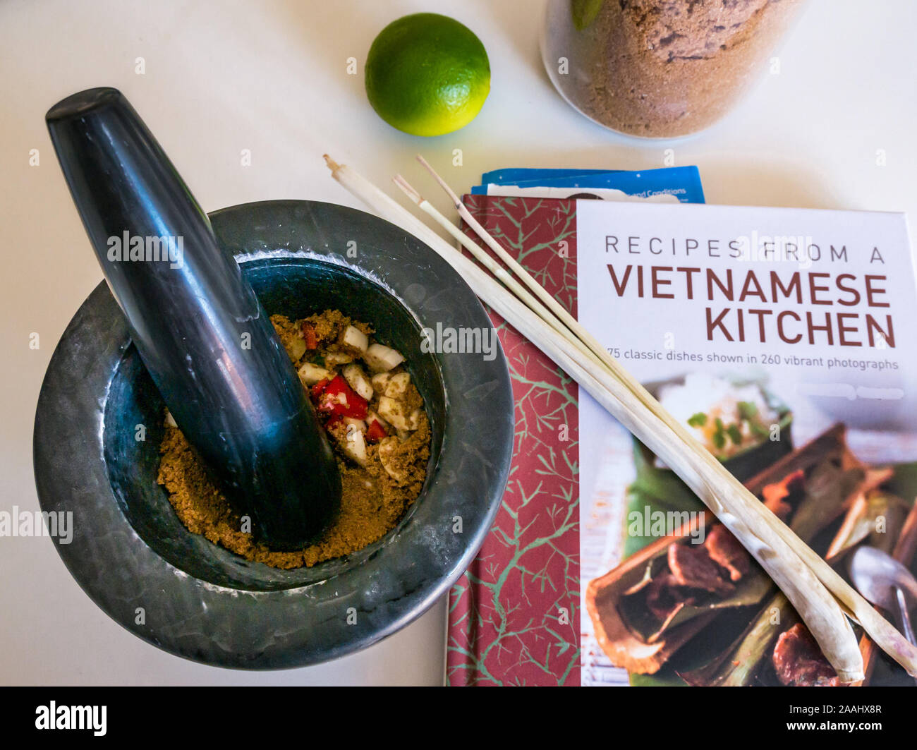 Stößel und Mörser & Zutaten für Nước chấm vietnamesische Dipping Sauce: Zitronengras, Limette & brauner Zucker. Vietnamesisches Kochbuch von Ghillie Basan Stockfoto
