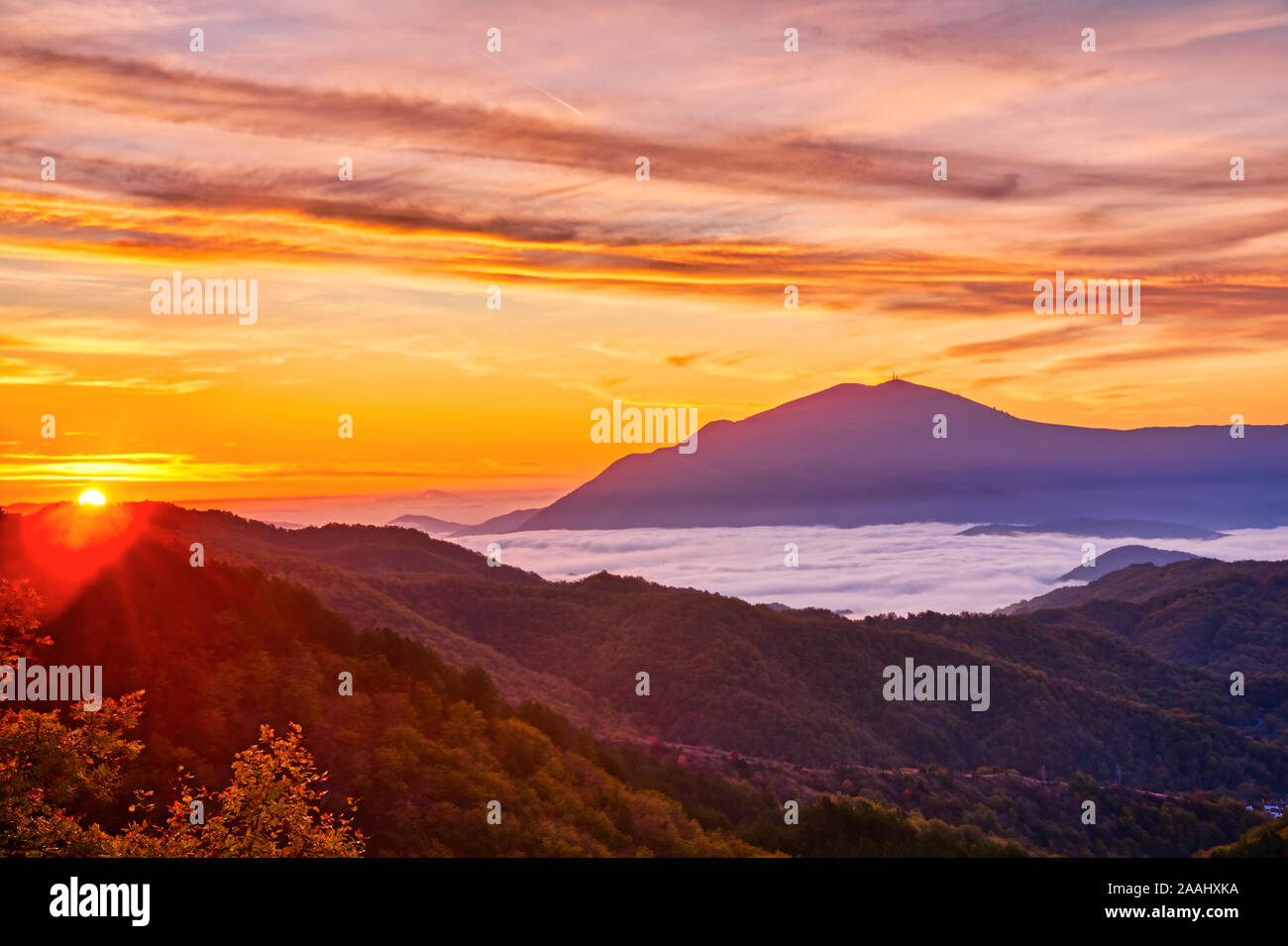 Erstaunlich Sonnenaufgang über neblige Landschaft. Malerischer Blick auf Nebligen Morgen Sky mit der aufgehenden Sonne über dem nebligen Wald. Rhodopen. Xanthi Thrakien, Griechenland Stockfoto
