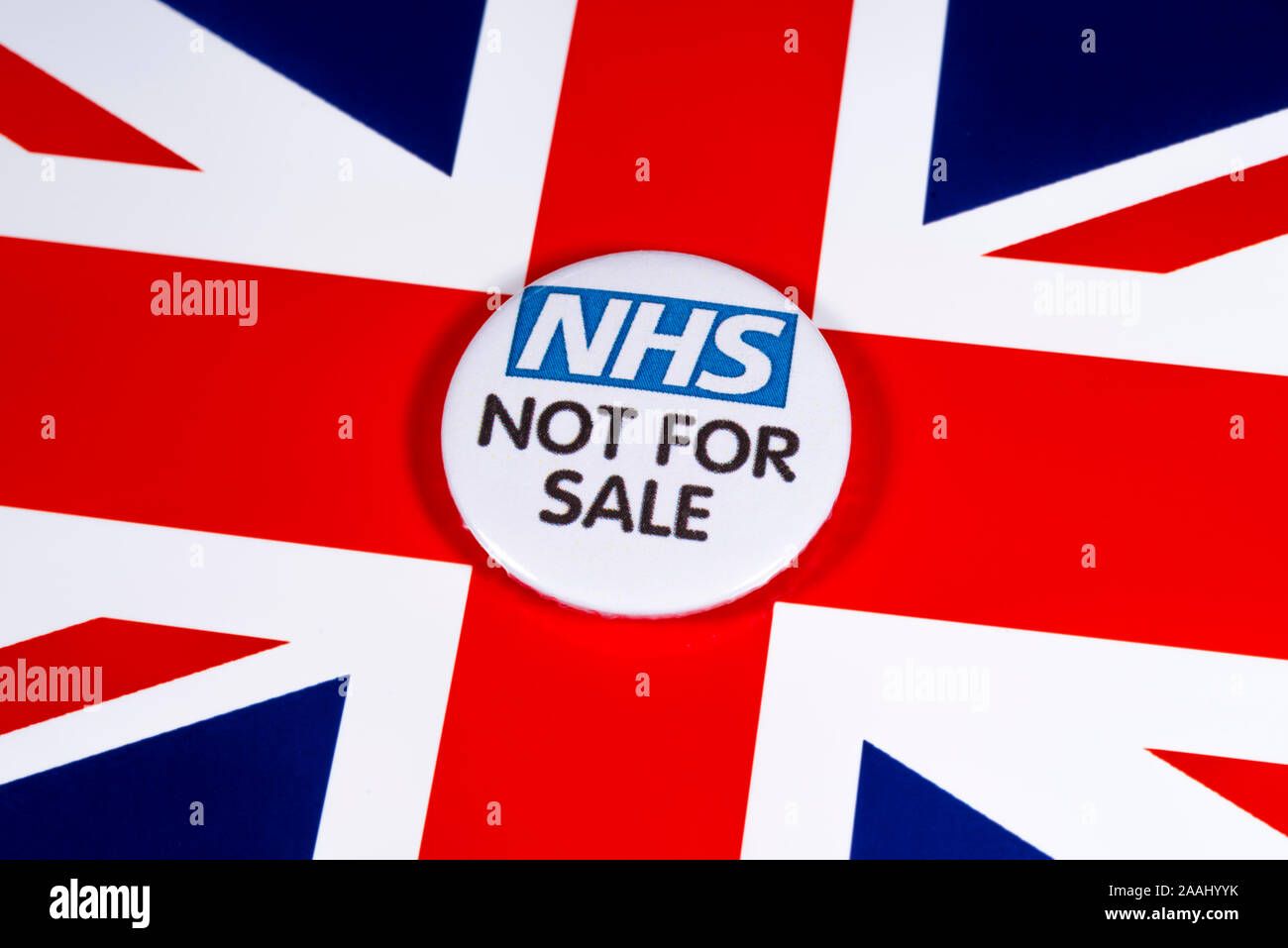 London, Großbritannien, 21. November 2019: Eine pin Badge verkünden, dass der Nationale Gesundheitsdienst ist nicht für den Verkauf, dargestellt über dem Vereinigten Königreich Flagge. Stockfoto