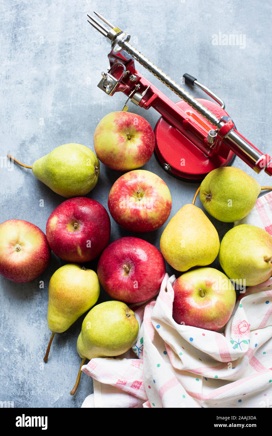 Apple peeler mit Äpfeln und Birnen auf Tisch Stockfoto