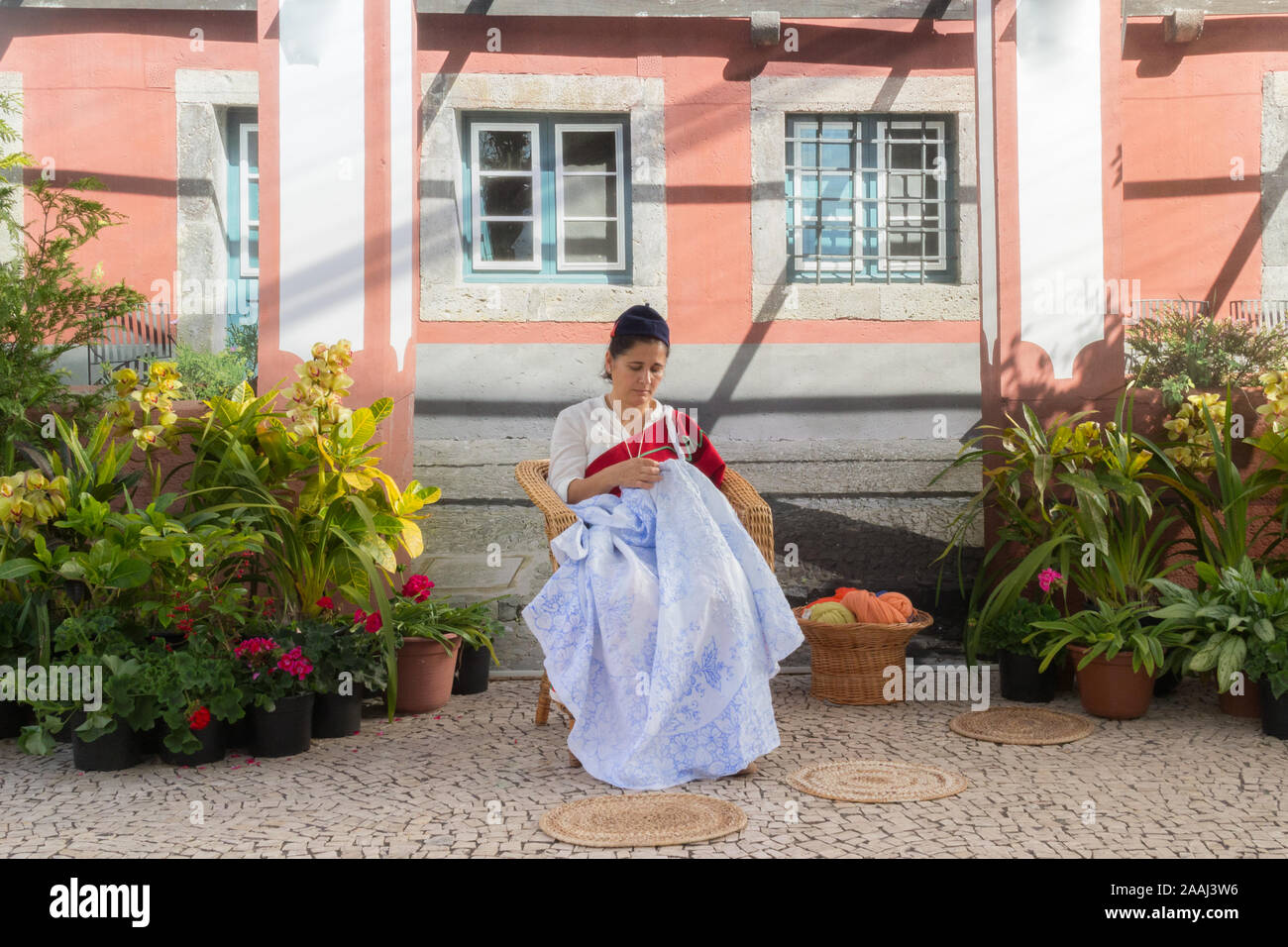 FUNCHAL, PORTUGAL - April 2018: eine Frau in einem traditionellen Kleid stickt eine Tischdecke durnig der Madeira Blumenfest in Funchal. Madeira isl Stockfoto