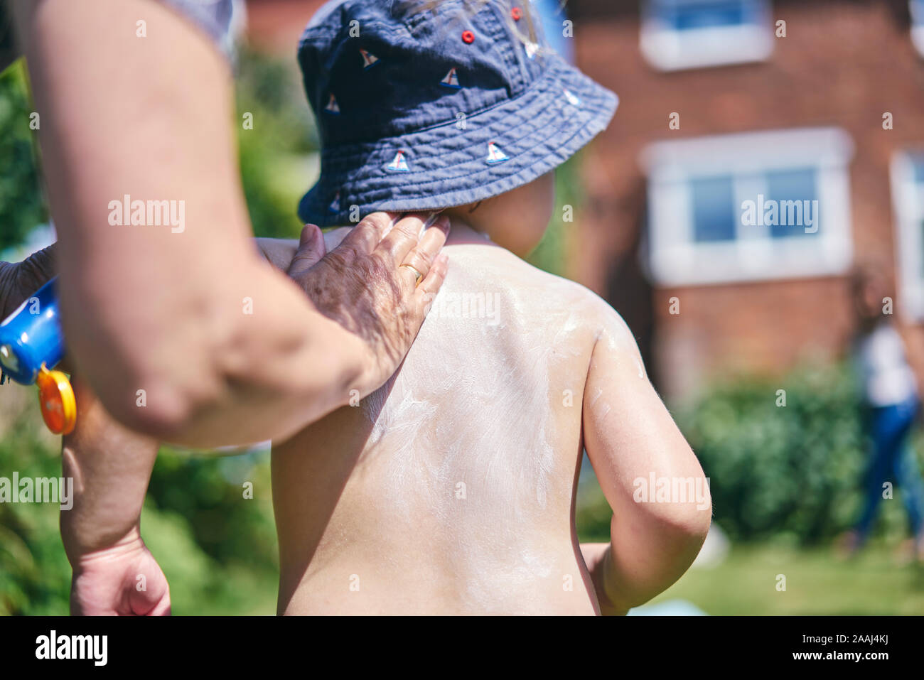 Großmutter putting Sun Lotion auf Enkel Stockfoto