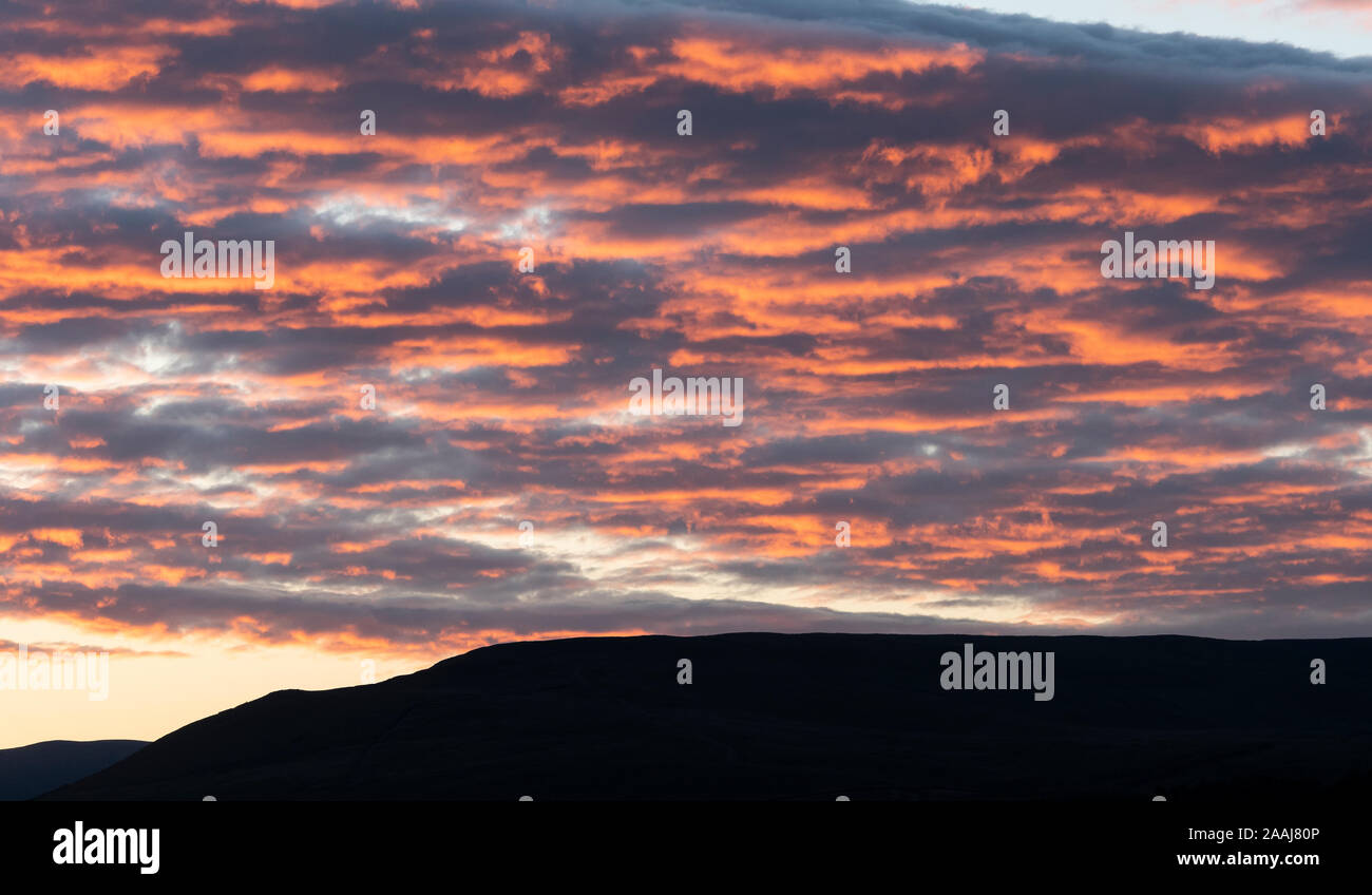 Wolken verfangen der Letzte Abendsonne und orange leuchtende, oberhalb der Yorkshire Dales in Wensleydale, UK. Stockfoto