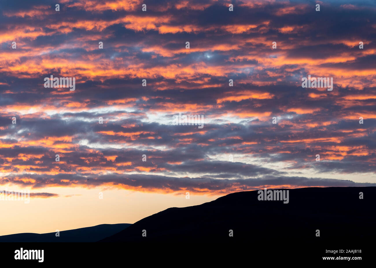 Wolken verfangen der Letzte Abendsonne und orange leuchtende, oberhalb der Yorkshire Dales in Wensleydale, UK. Stockfoto