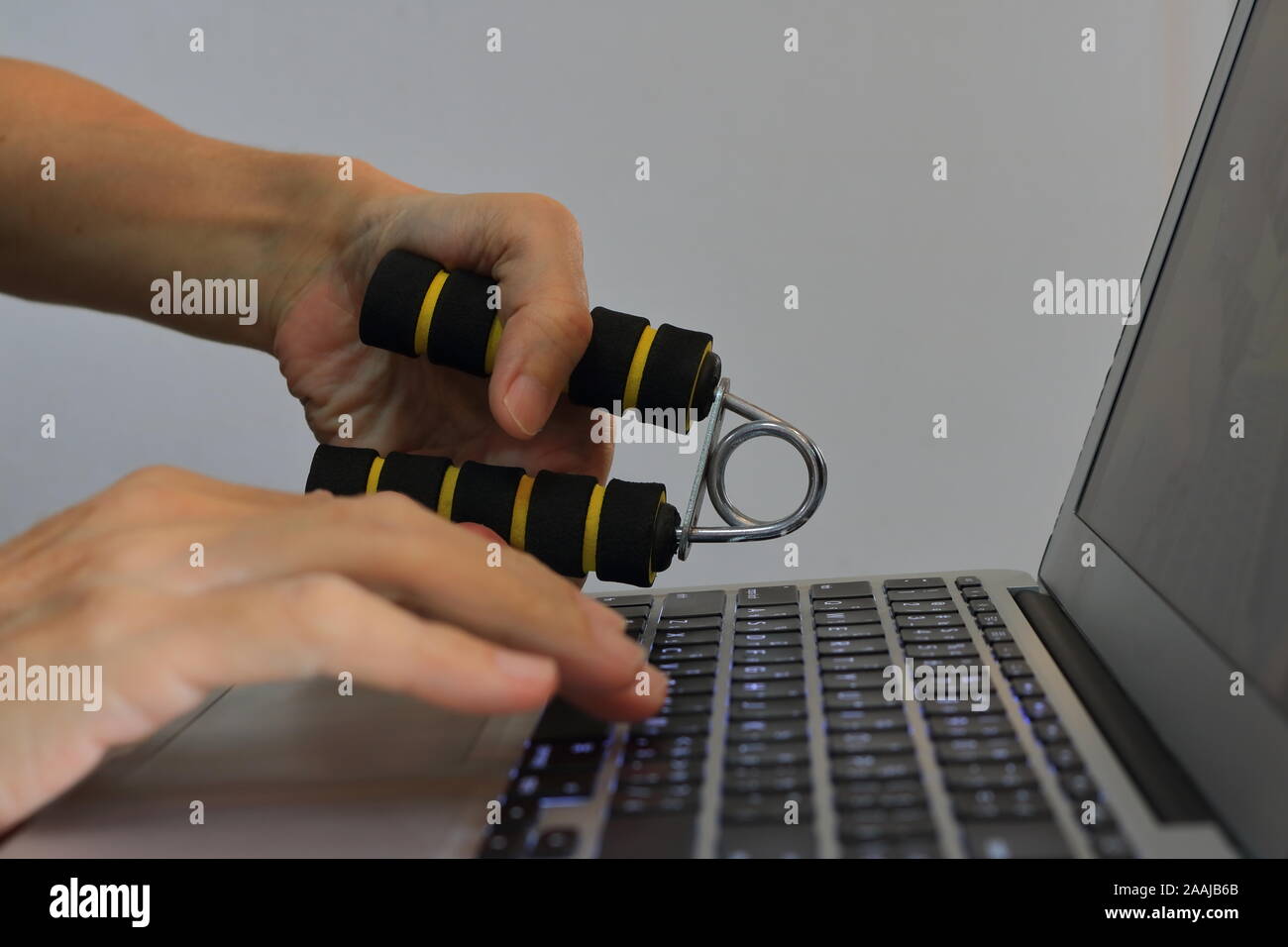Closeup Hand und quetscht hand Verstärkung während der Arbeit mit dem Notebook Computer, trainieren und gleichzeitig arbeiten Stockfoto