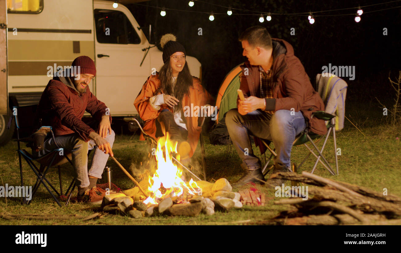 Brtiger Mann, ein lustiger Witz zu seinen Freunden rund um Lagerfeuer.  Retro Wohnmobil. Camping Zelt Stockfotografie - Alamy
