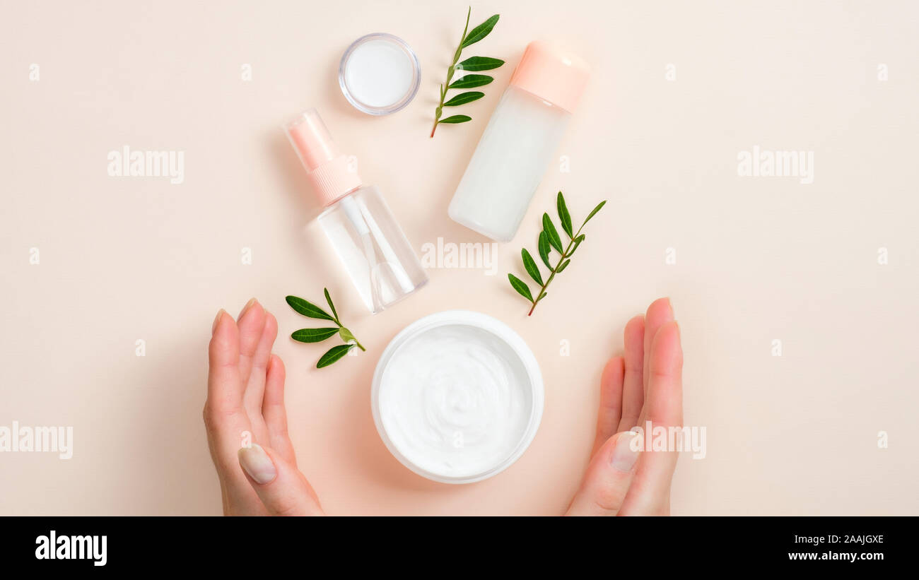 Jar von organischen Handcreme, ätherische Öle Flasche und grüne Blätter auf beigem Hintergrund. Hautpflege, Organic Natural Beauty Produkte Konzept Stockfoto