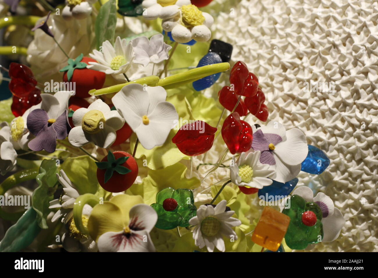 Das Bild zeigt eine vielfältige Auswahl an bunten Mann Tischdekorationen in Form von Blüten und Perlen auf weißem Gitter Stockfoto
