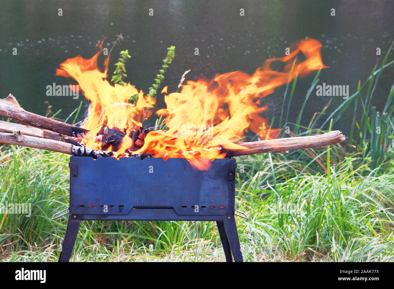 Brennholz Verbrennungen im Kühlergrill, Kohlen vorbereiten für das Grillen. Barbecue auf der Natur. Holzofen zubereitet für Grill. Das Grillen der Saison in der Nähe von See oder Fluss. Stockfoto