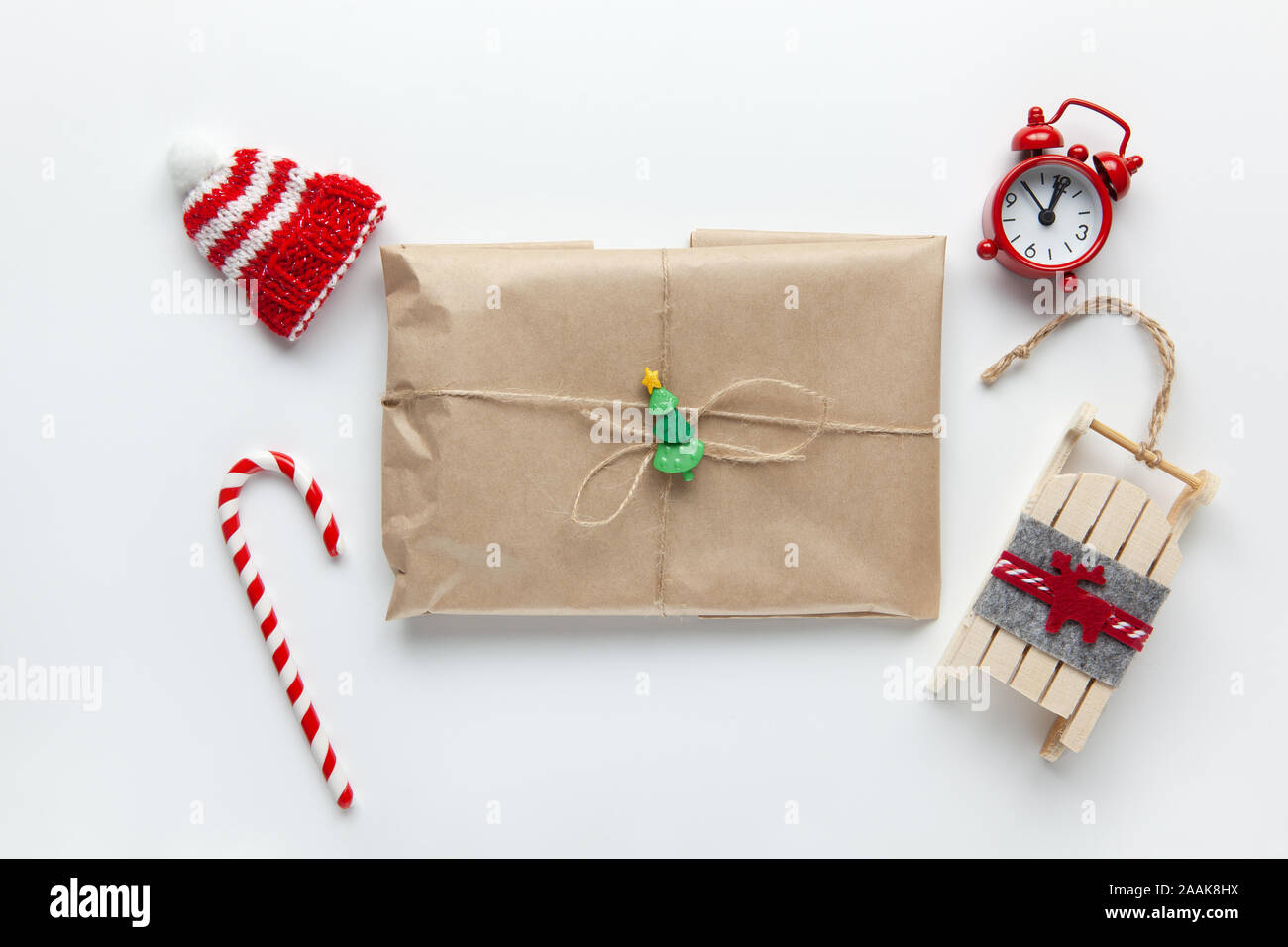 Weihnachten Geschenk verpackt in braun Handwerk Papier, mit der geissel  gebunden, mit Zuckerrohr Süßigkeiten, kleine analoge Uhr, Schlitten, Hut  auf weißem Hintergrund. Minimalistischer Stil. Top Stockfotografie - Alamy