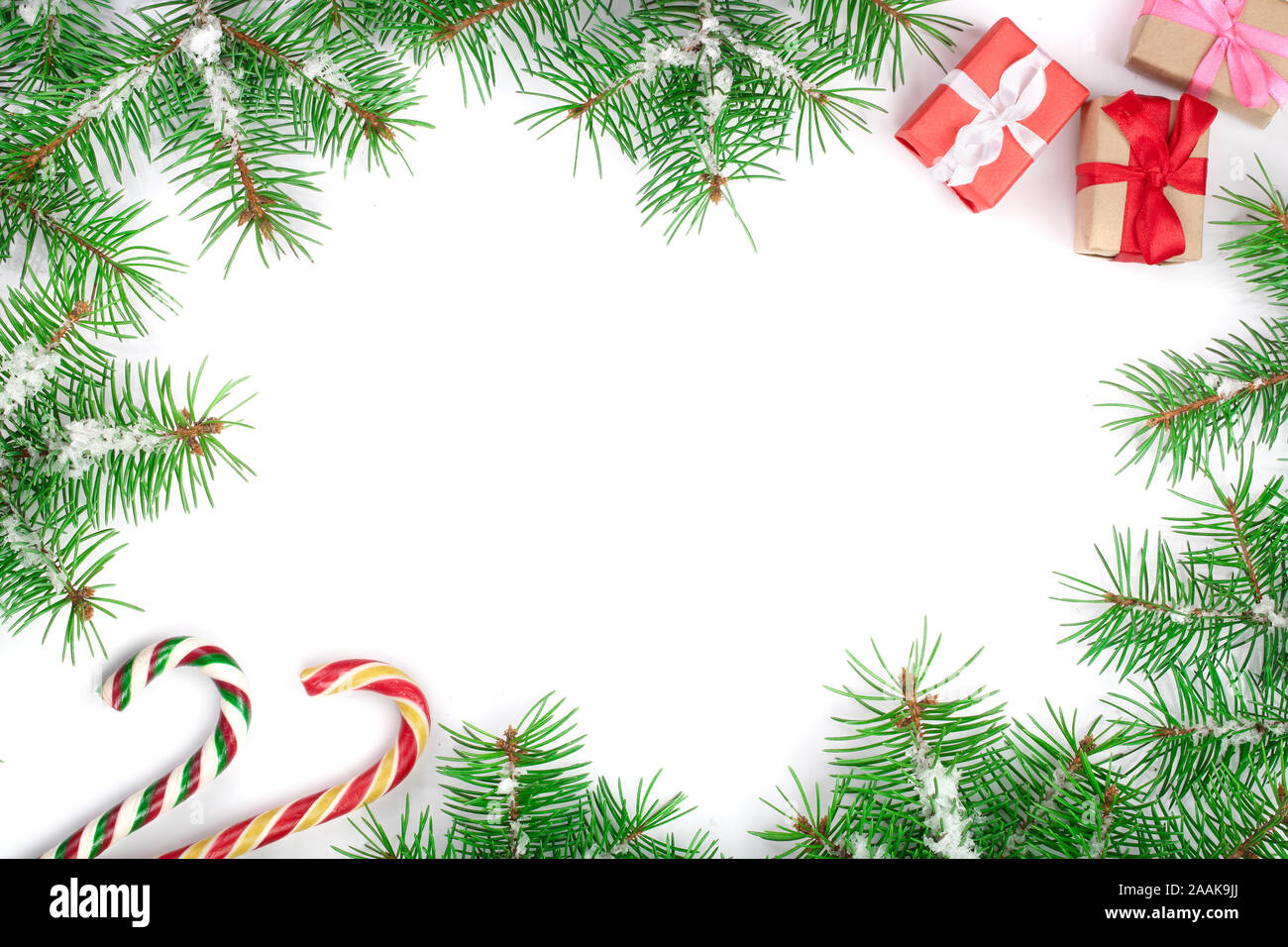 Weihnachten Rahmen der Fir Tree Branch mit Zuckerstangen und Schnee auf weißem Hintergrund mit Kopie Platz für Ihren Text isoliert. Ansicht von oben. Stockfoto