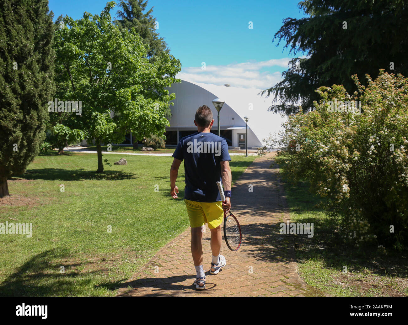 Mann mit einem Tennisschläger auf seinem Weg zur Tennishalle. Stockfoto